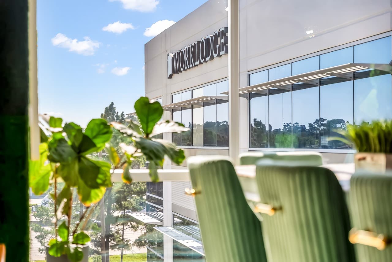 The WorkLodge building in Houston, seen through a window with green chairs and plants
